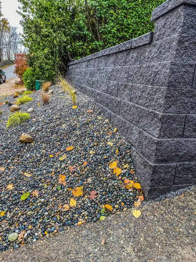 Segmental block retaining wall with a gravel bed at its base to help with yard pooling during an atmospheric river