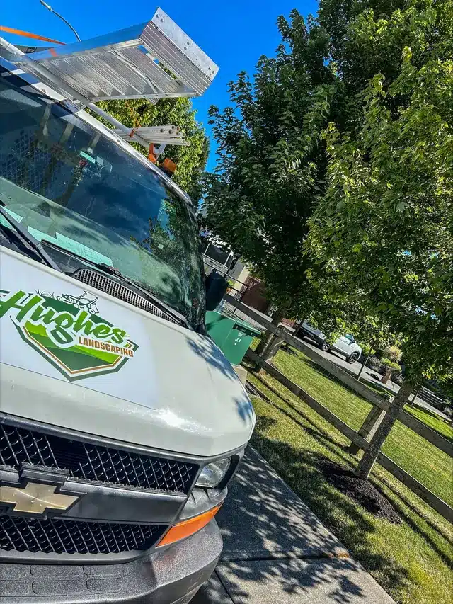 Hughes Landscaping service van parked beside a lawn and walkway